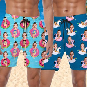 May include: Two pairs of blue and light blue swim trunks with a pattern of faces on inflatable pool floats. The pattern includes a unicorn, flamingo, and watermelon.
