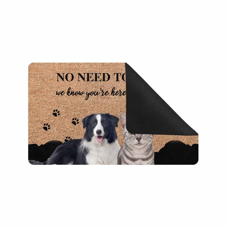 以下が含まれることがあります： 黒い文字で「NO NEED TO BARK, we know you're here」と書かれた茶色の玄関マット。黒と白のボーダーコリーと虎柄の猫がマットの上に座っています。