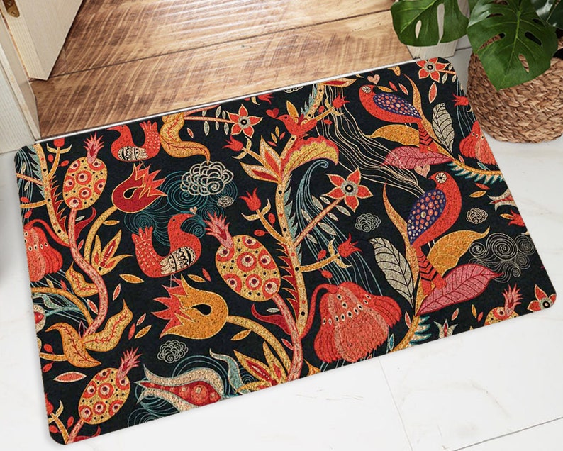 Puede incluir: Una colorida alfombra de bienvenida con un dise&ntilde;o floral y de p&aacute;jaros. La alfombra tiene un fondo oscuro con acentos rojos, naranjas, amarillos y azules. El dise&ntilde;o es intrincado y detallado, con una variedad de flores, hojas y p&aacute;jaros.