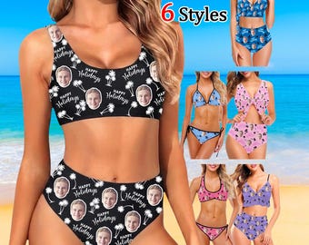 May include: A two-piece bikini set featuring a black background with a repeating pattern of white palm trees, the text "Happy Holidays," and circular portraits of a face. The set includes a scoop-neck crop top and high-waisted bikini bottoms.