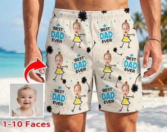 May include: Cream-colored swim trunks with a repeating pattern of a baby in a yellow dress, palm trees, and the text "BEST DAD EVER" in blue. The shorts are worn by a person on a beach.