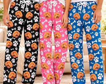 May include: Three pairs of lounge pants featuring a repeating pattern of brown dog faces, white paw prints, and white bones. The pants come in black, pink, and blue, each with a white drawstring at the elasticized waistband.