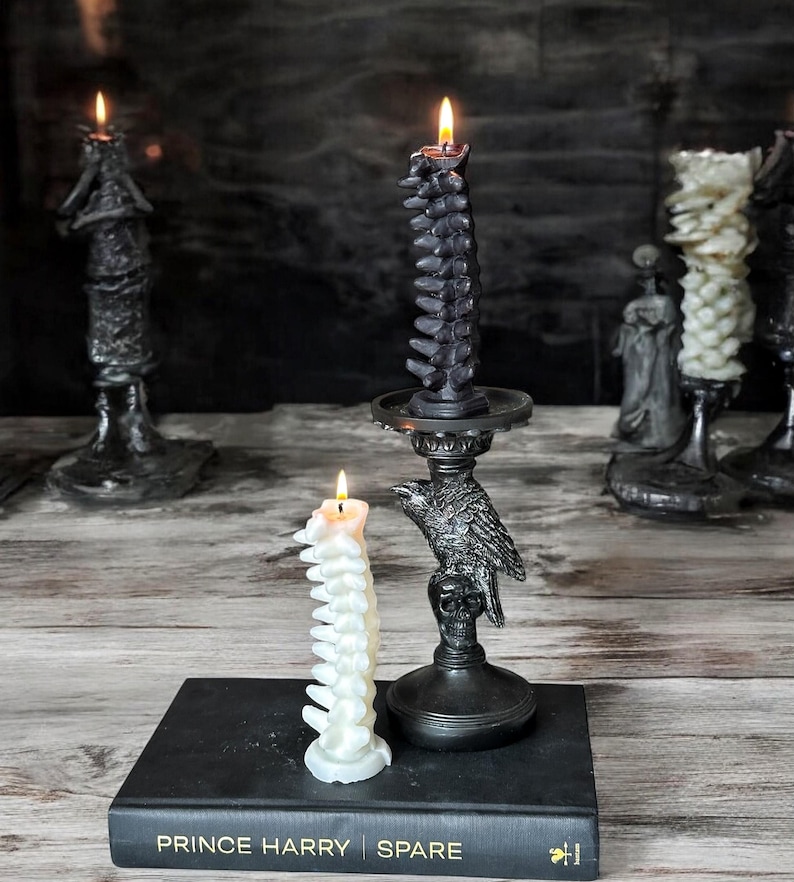 Pode incluir: Duas velas em forma de espinha dorsal, uma preta e outra branca, em casti&ccedil;ais pretos. A vela preta est&aacute; em um casti&ccedil;al em forma de corvo. As velas est&atilde;o em um livro intitulado "Prince Harry Spare".