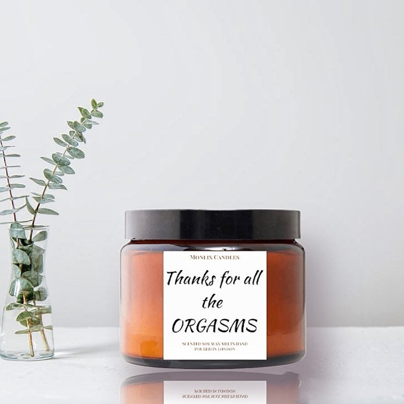 May include: A brown glass candle jar with a black lid. The label reads "Thanks for all the ORGASMS" and "Scented Soy Wax Hand Poured in London".