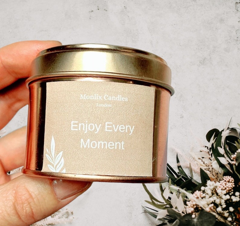 May include: A gold tin candle with a beige label that reads "Monlix Candles London" and "Enjoy Every Moment".