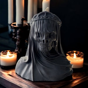 May include: A black candle in the shape of a hooded figure with a crown. The candle is surrounded by other candles.