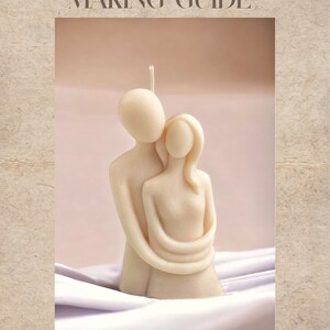 May include: A white couple's candle, sculpted in an embrace, sits on a white fabric surface. The candle is a romantic gift idea for couples.