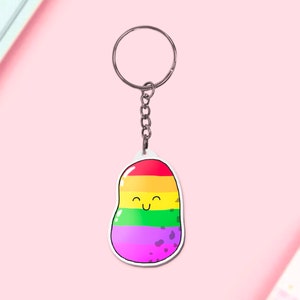 May include: A rainbow-colored potato keychain with a happy face. The potato is made of acrylic and has a silver key ring.