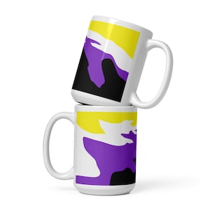 Puede incluir: Dos tazas de cerámica blanca apiladas una encima de la otra. La taza superior tiene un diseño abstracto amarillo, blanco y morado. La taza inferior tiene un diseño abstracto amarillo, blanco y morado.