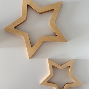 Peut inclure: Deux décorations murales en bois en forme d'étoile. La plus grande étoile mesure environ 30 cm de large et la plus petite étoile mesure environ 15 cm de large. Les deux étoiles sont en bois naturel et ont une couleur brun clair.