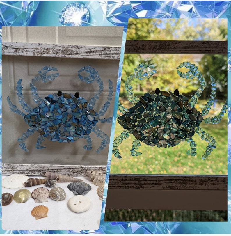May include: A blue crab mosaic made from small pieces of iridescent glass. The crab is displayed in a white frame with a rustic wood finish.