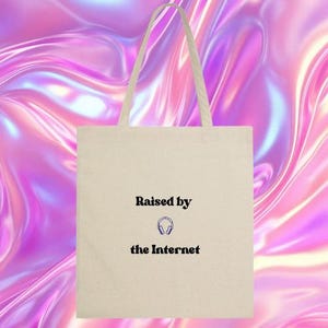 Peut inclure: Un sac fourre-tout blanc avec du texte noir qui dit "Raised by the Internet" et un petit graphique de casque audio.