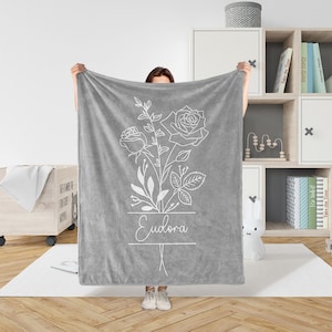Peut inclure: Jet&eacute; de canap&eacute; en polaire gris avec un contour blanc d'un bouquet de roses et le nom "Eudora" imprim&eacute; dessus.