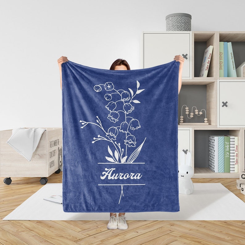 Peut inclure: Une couverture en polaire bleue avec un motif floral blanc et le nom "Aurora" imprim&eacute; dessus.