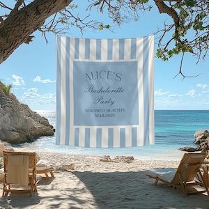 Peut inclure: Une serviette de plage ray&eacute;e bleu et blanc avec le texte "Alice's Bachelorette Party Seacrest Beach FL MAR 2025" imprim&eacute; dessus. La serviette est accroch&eacute;e &agrave; une branche d'arbre au-dessus d'une plage avec deux chaises longues.