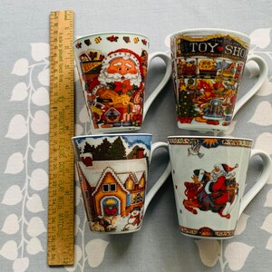 May include: Four ceramic mugs with Christmas-themed designs. The mugs feature Santa Claus, a toy shop, a winter village, and Santa Claus riding a reindeer. The mugs are white with colorful designs.
