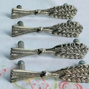 May include: Four silver-toned cabinet knobs with a wheat sheaf design. Each knob has a small, round, light blue base.