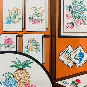 May include: A set of embroidery patterns featuring various kitchen-themed designs. The patterns include a pineapple with grapes and cherries, a pitcher with cherries, a teapot with grapes, a salt shaker, a floral design with strawberries, and a floral design with grapes. The patterns are printed on white fabric and are ready to be stitched.