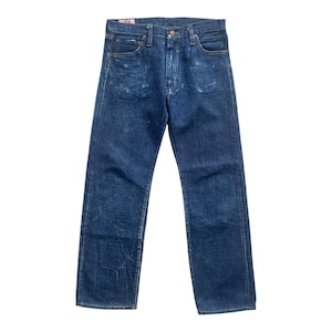 May include: A pair of dark blue denim jeans featuring a straight-leg cut, a classic five-pocket design, a button fly closure, and a visible red brand label on the interior waistband. The fabric shows subtle fading and whiskering patterns throughout.