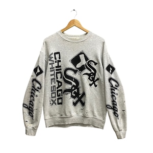 May include: Gray sweatshirt with a black and white graphic print of the Chicago White Sox logo. The logo is on the front of the sweatshirt and the words "Chicago White Sox" are printed on the left sleeve. The words "Chicago" are printed on the right sleeve.