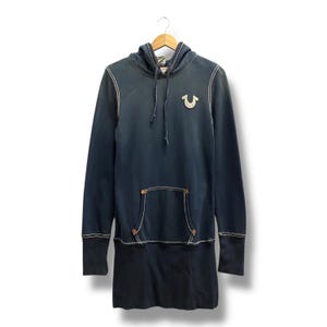 Puede incluir: Vestido sudadera con capucha azul marino con costuras blancas. Cuenta con un bolsillo de canguro, un pequeño logotipo en el pecho y una capucha con cordón. El vestido tiene mangas largas y un bajo azul oscuro contrastante.