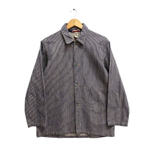 May include: A blue and white striped jacket with a collared neckline and button-up front. The jacket is hanging on a wooden hanger. The jacket has two front pockets and long sleeves.