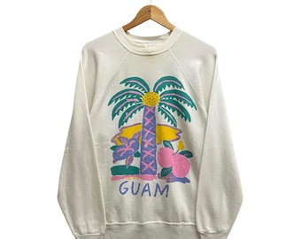 Op de afbeelding: Een wit sweatshirt met een kleurrijke afbeelding van een palmboom, fruit en het woord "GUAM".