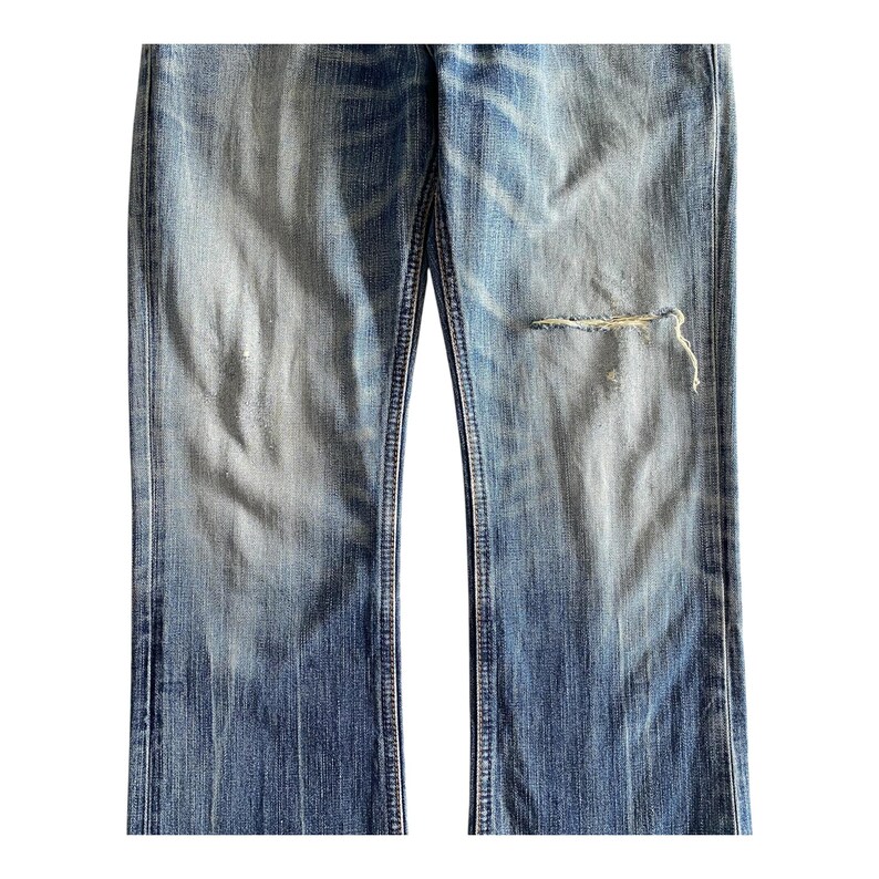 Pu&ograve; includere: Un paio di jeans blu con un ginocchio consumato. I jeans hanno un aspetto sbiadito e sono realizzati in un materiale morbido e confortevole.
