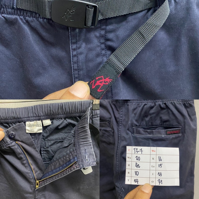 May include: Navy blue pants featuring an integrated black nylon belt with a plastic buckle, an elastic waistband, a metal zipper fly, and a Gramicci brand label. A white paper tag displays handwritten measurements in inches for waist, hip, and length.