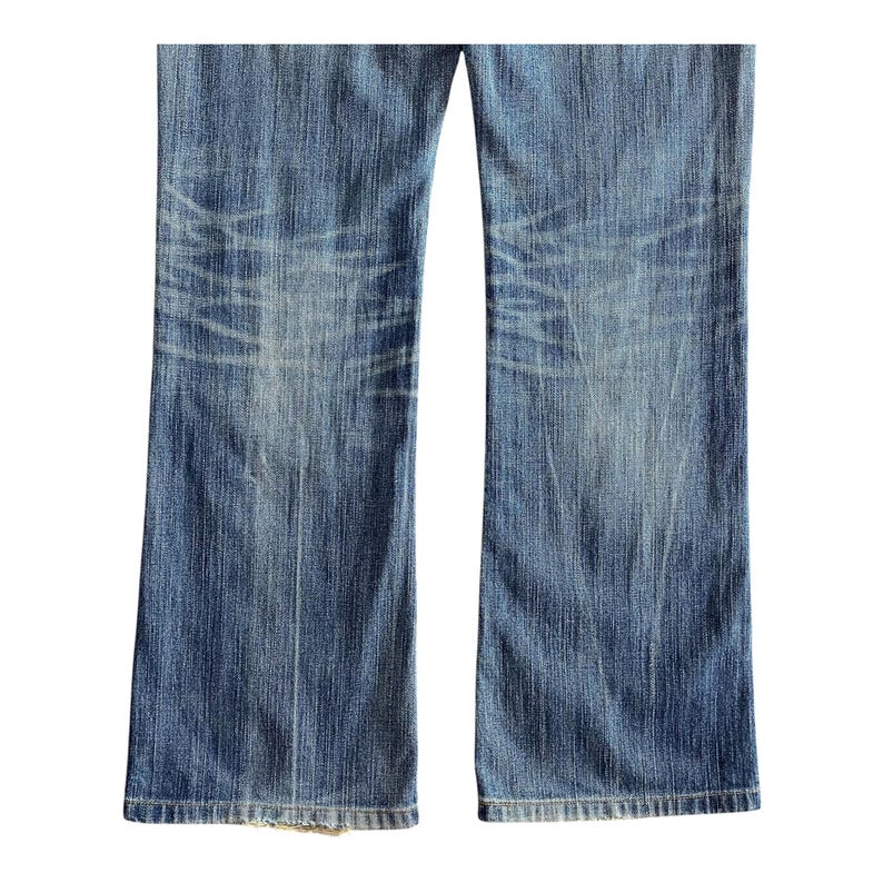 Pu&ograve; includere: Un paio di jeans blu denim con un aspetto sbiadito e rovinato. I jeans hanno una gamba dritta e un lavaggio chiaro.