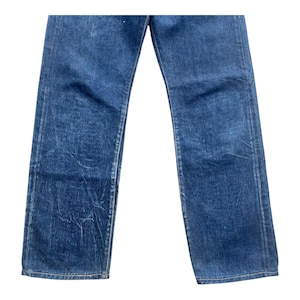 May include: A pair of dark blue denim jeans featuring a straight-leg cut with visible fading and whiskering patterns throughout the fabric. The denim has a classic five-pocket construction with reinforced stitching along the seams and hems.