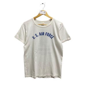 May include: A white t-shirt with a blue arched graphic that reads "U.S. AIR FORCE".