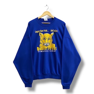 May include: Royal blue sweatshirt featuring a cougar graphic and the text "Cougars Have Pride... And So Do I." The text "Robert Frost Elementary School" is below the graphic.