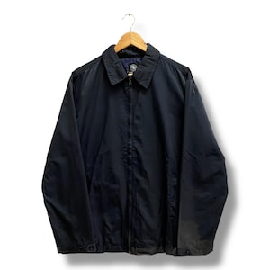 May include: A black jacket with a collared neckline and a zip closure. The jacket is suspended from a wooden hanger. The jacket features two pockets and button fastenings on the sleeves. The jacket is made of a smooth, possibly nylon, material.