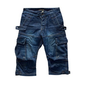 May include: Dark blue denim cargo capris featuring a mid-rise waist, a button and zipper fly closure, and multiple utility pockets on the thighs. These cropped pants include adjustable straps at the leg openings and reinforced stitching throughout.