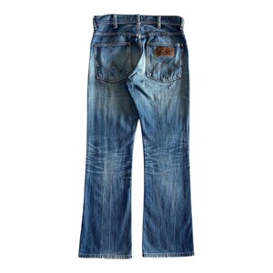 Pu&ograve; includere: Un paio di jeans blu denim con una toppa in pelle marrone sulla tasca posteriore.