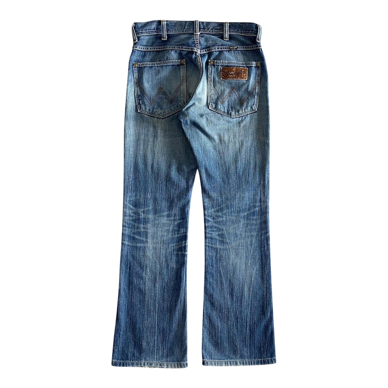 Pu&ograve; includere: Un paio di jeans blu denim con una toppa in pelle marrone sulla tasca posteriore.