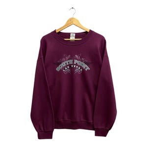Könnte beinhalten: Burgunderfarbener Sweatshirt mit einem grauen gestickten Logo, auf dem "South Point Las Vegas" steht.