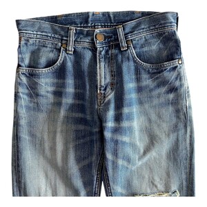 Pu&ograve; includere: Un paio di jeans blu in denim con dettagli sbiaditi e consumati. I jeans hanno uno stile classico a cinque tasche e una chiusura con bottone.