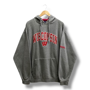 May include: A gray hoodie with the word "WISCONSIN" in red arched lettering across the chest, with a red "W" underneath. The hoodie has a front pocket and a drawstring hood. The word "BADGERS" is on the right sleeve.