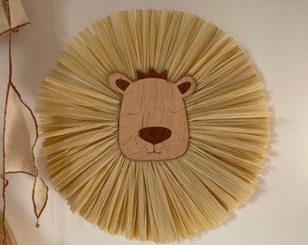 May include: A wooden lion head with a crown, surrounded by a large, beige, straw-like mane. The lion's eyes are closed and it has a small, brown nose.