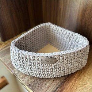 May include: A light gray crocheted triangular basket with a silver label that says "Aminale".