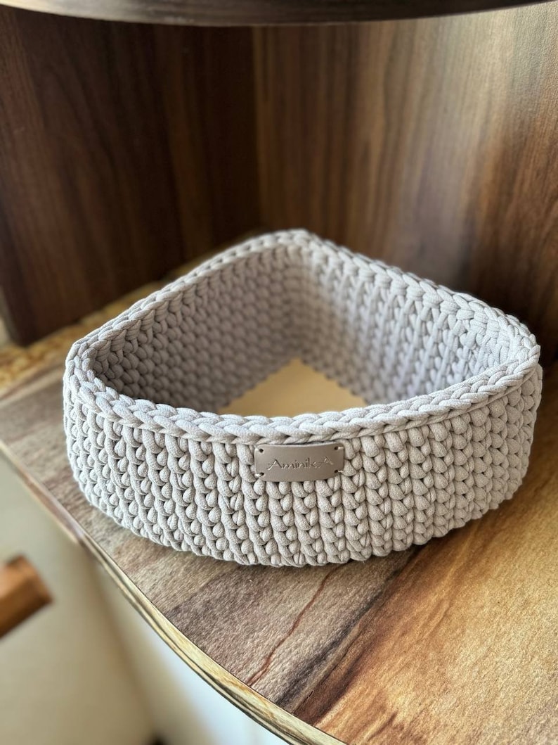 May include: A light gray crocheted triangular basket with a silver label that says "Aminale".