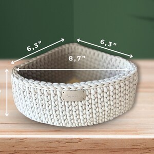 May include: A white crocheted storage basket with a rectangular label that says "Amolle" in silver lettering. The basket measures 8.7 inches wide, 6.3 inches long, and 3.9 inches high.
