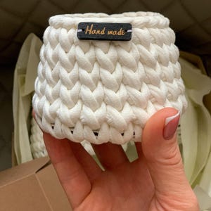 May include: White crocheted basket with a black tag that says "Hand made".