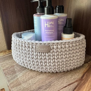 May include: A light gray crocheted basket with a silver label that says "Aminila" is filled with various bottles of kids beauty products. The bottles are labeled "mini kids beauty" and include a nourishing shampoo, micellar cleanser, and a spray bottle.