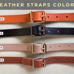 Pu&ograve; includere: Quattro cinturini in pelle arancione, nera, beige e marrone, ciascuno con una fibbia in metallo. I cinturini sono etichettati con i loro colori. Il testo "LEATHER STRAPS COLORS" &egrave; in alto.