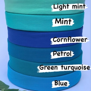 May include: Six rolls of fabric in different shades of blue and green. The colours are labelled from top to bottom: Light mint, Mint, Cornflower, Petrol, Green turquoise, and Blue.