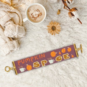 Pode incluir: Um bracelete de contas roxas com fechos dourados e um design de contas que diz "Pumpkin Spice". O bracelete apresenta pequenas contas laranja de abóbora e xícara de café.