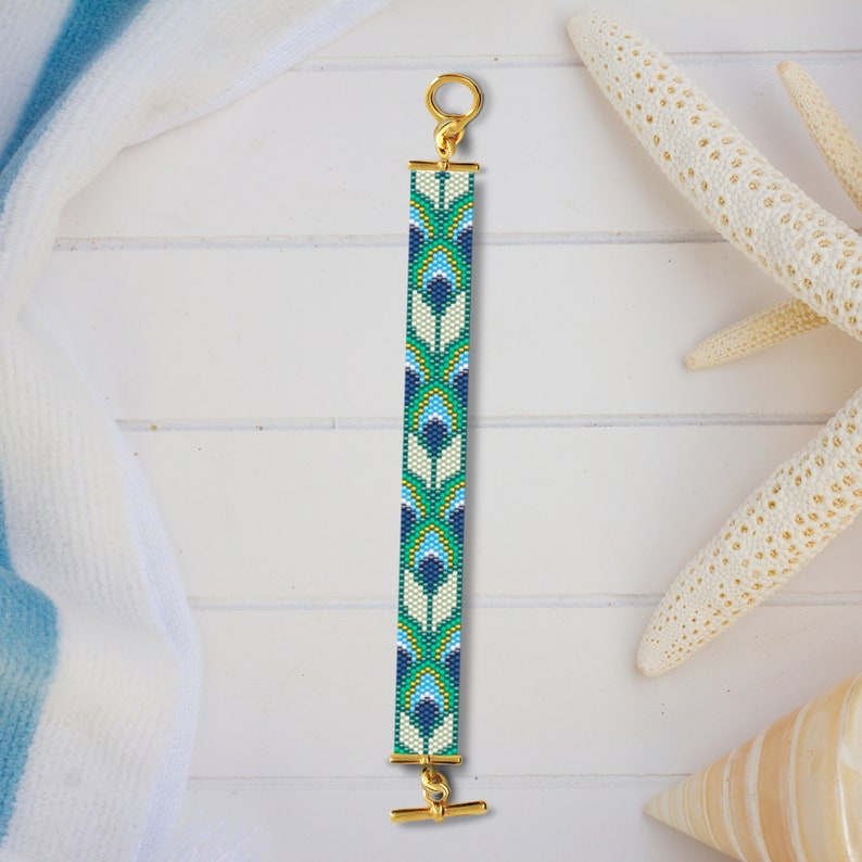 May include: A beaded bracelet with a geometric pattern in shades of blue, green, and white. The bracelet has a gold clasp and a toggle closure.